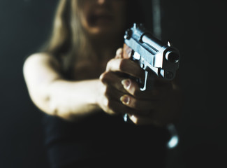 Adult girl pointing a gun ready to shoot