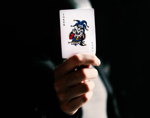 Hand holdign a joker card - obrazy, fototapety, plakaty