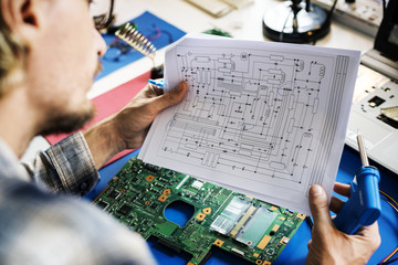 Technicians working holding electronics circuit guide paper