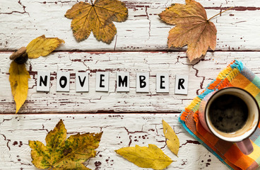 Close up of yellow leaves and corns on rustic white wooden background. Cup of coffee americano with...