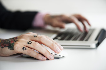 Hands with tattoo typing on a keyboard