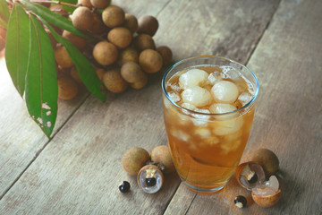 Longan drink with fresh fruit peel the skin show white meat and black seed on a wooden background.