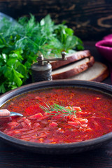 Hot soup with beets and sour cream in a clay bowl, selective focus