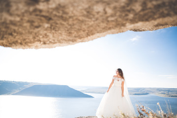 Fototapeta na wymiar Pretty lady, bride posing in a wedding dress near sea on sunset