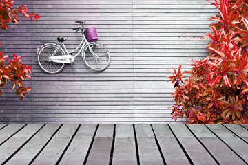 Image of wooden table in front of bicycle lying on wooden floor with trees along the way from top view, can used for display or montage your products.