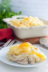 Potato Gratin with onion and pork on a white plate, selective focus