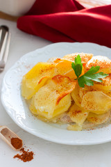 Potato Gratin with onion and pork on a white plate, selective focus