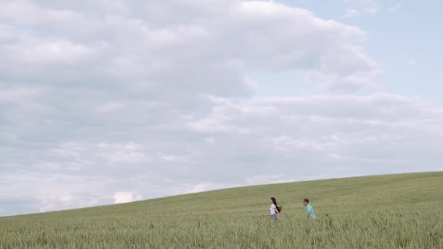 A happy girl runs away from her boyfriend. Wheat field.