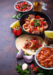Concept of Mexican food.  Salsa, tortilla, beans, fajitas and tequila