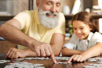 Grandfather and granddaughter joining two jigsaw puzzle pieces