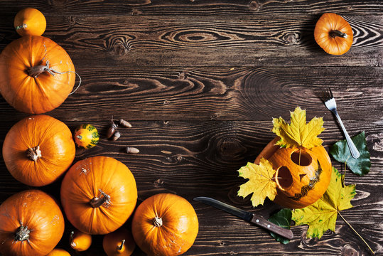 Halloween pumpkin man with knife and fork over wooden background, top view, flat lay with copy space for text, toned image