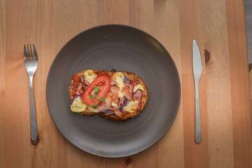 Delicious seasoned savory Italian tomato bruschetta slices on a rustic wooden board garnished with fresh basil leaves.