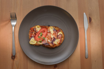 Delicious seasoned savory Italian tomato bruschetta slices on a rustic wooden board garnished with fresh basil leaves.