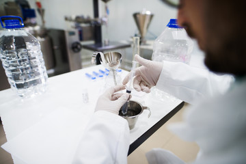 Rear view of a scientist with glasses having test with the syringe.
