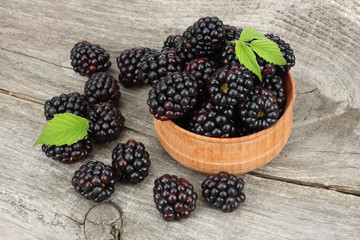 blackberries in wooden bowl on old wooden table background