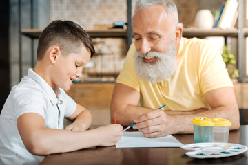 Happy boy painting a picture together with his grandfather