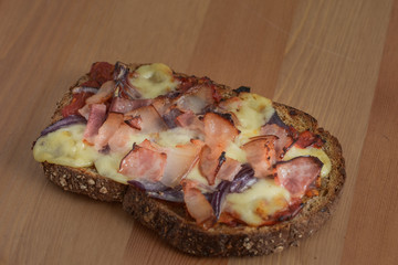 Delicious seasoned savory Italian tomato bruschetta slices on a rustic wooden board garnished with fresh basil leaves.