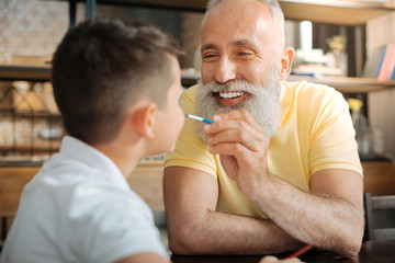 Happy grandfather painting nose of his grandson