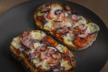 Delicious seasoned savory Italian tomato bruschetta slices on a rustic wooden board garnished with fresh basil leaves.