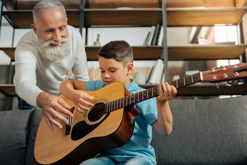 Obraz premium Loving grandfather and grandson having guitar practice