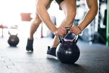 Unrecognizable fit man in gym doing push ups on kettlebells