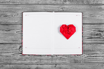 Heart of origami of red paper. Open notebook with clean pages and a paper heart. Templates and backgrounds