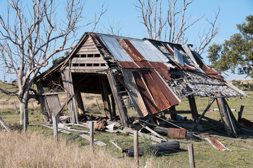 Old timber barn with metal roof damaged after severe storm