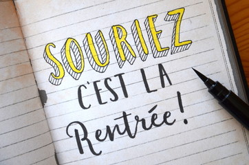 « SOURIEZ, C’EST LA RENTREE » lettrage à la main sur cahier