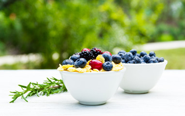 Delicious healthy breakfast in the garden. Corn flakes and forest berries. Blueberries and blackberries