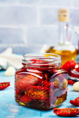 Fototapeta na wymiar Dry tomatoes with spices and garlic in glass jars on kitchen table