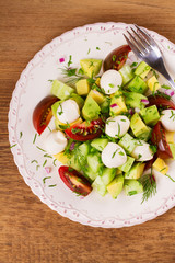 Avocado salad with tomato, cucumber and mozzarella. Cheese and vegetable salad. View from above, top studio shot