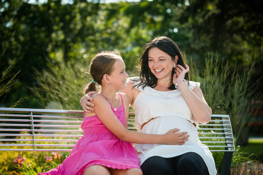 Happy pregnant woman with her girl child. Outdoor shot.