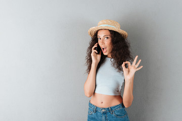 Surprised lady in hat talking on smartphone