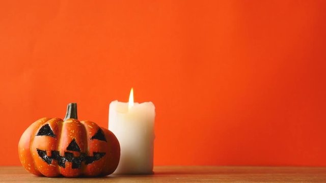 Halloween pumpkin with candlelight on an orange color background. Free space for text 