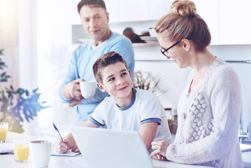 Careful mother helping son with homework at home