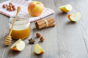 Jar of honey, honey stick, cinnamon, hazelnuts and red apple