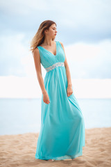 Fototapeta na wymiar Beautiful young girl in a light blue long dress on the beach 