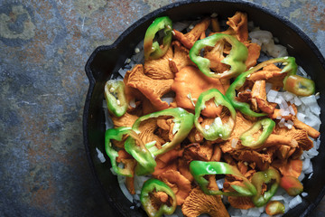Mushrooms chanterelles, onion and pepper in a frying pan close-up