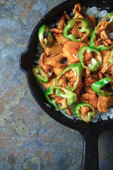 Mushrooms chanterelles, onion and pepper in a frying pan on the right