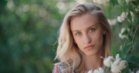 Woman in spring blossom. Young naturally beautiful woman near the blooming tree in spring time. Eco beauty and health concept.