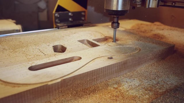 Manufacture of guitars. Milling a guitar deck on a machine with numeric control programs.