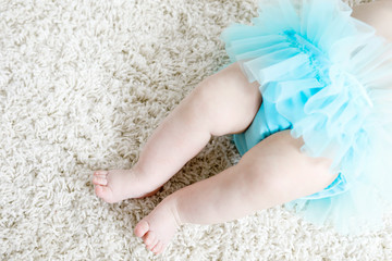 Close up of legs and feet of baby girl on white background wearing turquoise tutu skirt. © Irina Schmidt