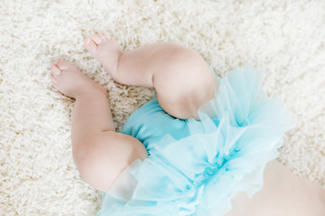 Close up of legs and feet of baby girl on white background wearing turquoise tutu skirt. © Irina Schmidt