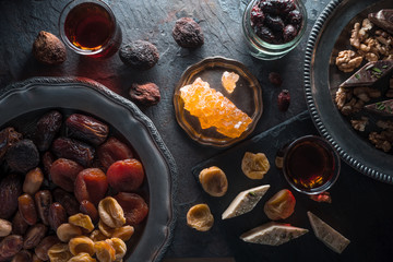 Dried fruits, nuts on a plate and tea on a gray shale