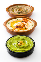 Different hummus bowls. Chickpea hummus, avocado hummus and lentils hummus isolated on white background
