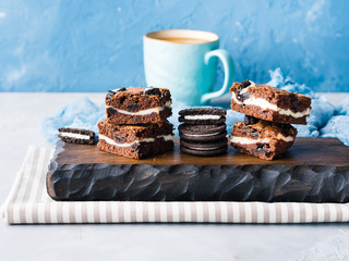 Cream cheese chocolate layer brownies with cookies on wooden serving board