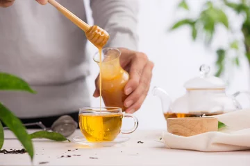 Verdunkelungsvorhänge Tee Abgeschnittenes Bild von Arista, der Honig in eine Tasse Tee gießt