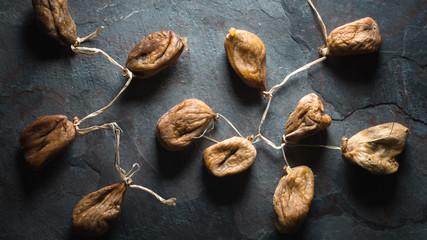Dried beige figs with a string on a gray stone