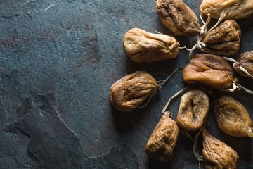 Dried beige figs with a string on a gray stone on the right
