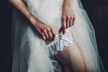 The bride adjusts the wedding garter on her leg